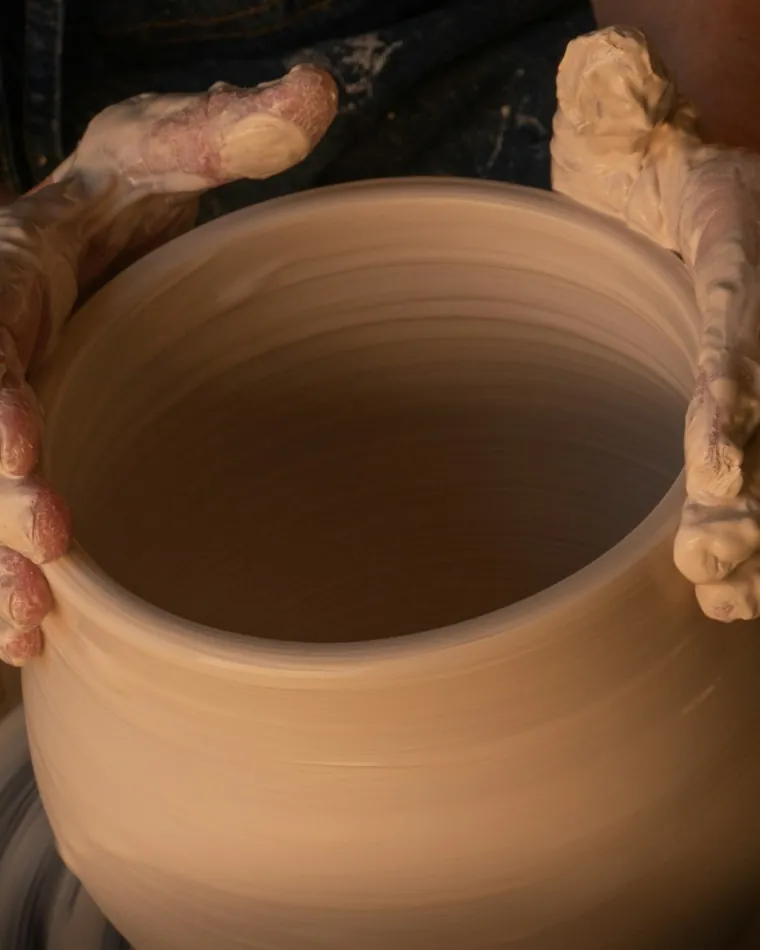 Mani che sostengono un pezzo in ceramica bianca appena estratto, con la parete ancora umida