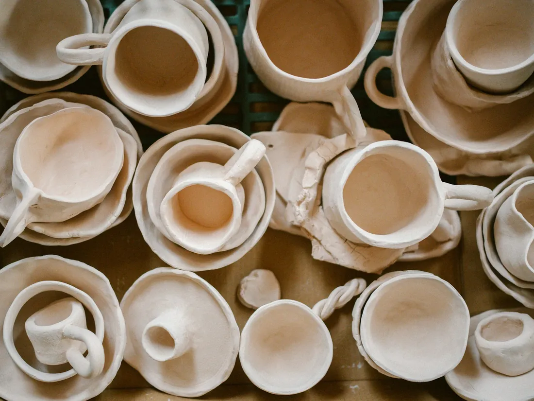 File di tazze in ceramica non ancora smaltate appoggiate su un piano di lavoro in laboratorio